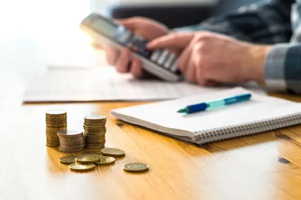 Calculating finances with coins, calculator, and notepad.